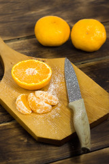 orange on a cutting board and a wooden background with a knife