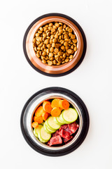 Healthy feed for cats and dogs. Bowls full of dry feed, meat and vegetables on white background top-down