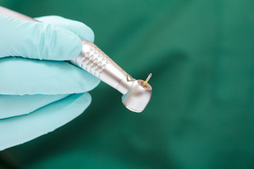 Dentist's hand in glove with dental handpiece.