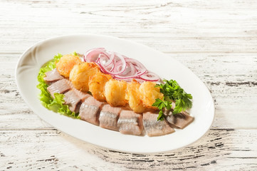 Potato herring close-up. Potato pancakes and herring on a white plate and copy space.