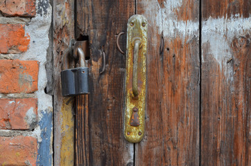 An old rusty padlock on a wooden door, close-up, soft focus.