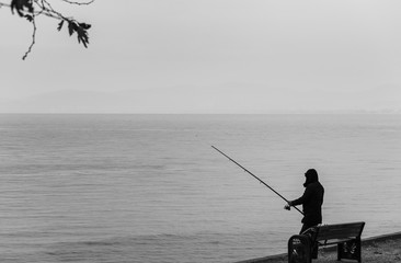 Silhouette of fisherman at sunset. Black and white seascape. Silhouette of people as blots....