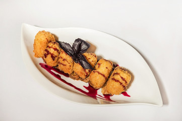 Camembert in a restaurant close-up. Fried breaded camembert with berry sauce on a white plate and copy space.