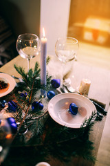 Table served for winter dinner in living room. Close up view, table setting. Christmas and winter decorations in blue colors. Beautiful served table with decorations