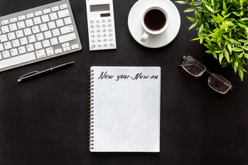 New year new me motto - motivation concept. Notebook for goals and plans on black office desk top-down copy space mockup