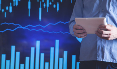 Businessman holding tablet and working in financial graphs in screen.