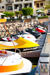 Fototapeta na wymiar bright boats, scooters in the Marina