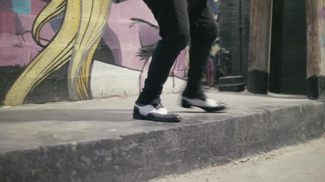 Unrecognizable street artist dancing on a pavement. Feet close up