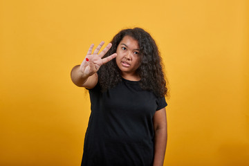 Charming afro-american woman showing three fingers at camera over isolated orange background wearing fashion black shirt. People lifestyle concepte.