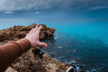 Blurred male hand on a background of sea and rocks. Relaxation by the sea. Landscapes of Cyprus