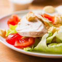 Salad with grilled chicken, vegetables and egg in a white plate