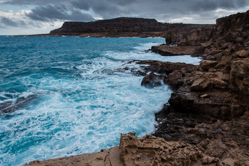 Restless turquoise sea in Cyprus, Cape Greco. The waves crash into the rocky shore