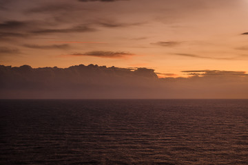 Sunset in Cyprus, Cape Greco. Calm dark sea and orange sky with clouds