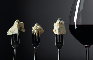 Pieces of blue cheese on a forks and red wine.