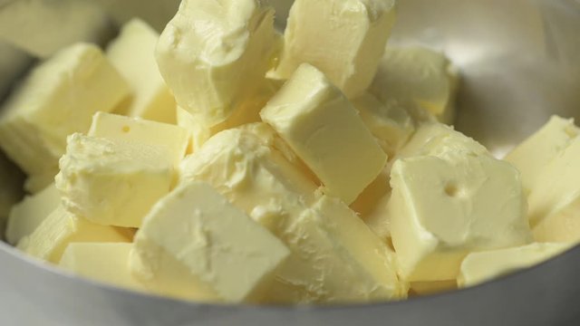 Close up adding cube cut butter to a metal bowl.