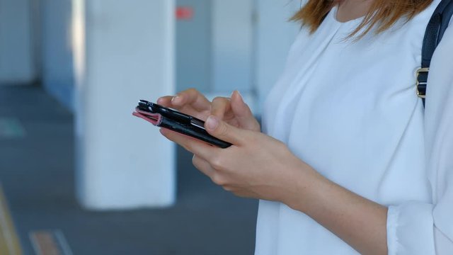 駅のホームでスマートフォンを操作する女性　携帯　ゲーム　電車待ち