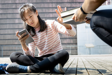 Asian child girl is avoiding reading book, say no,she wants to use a mobile phone to play games or...