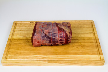 Rolled beef brisket on a wooden chopping board.