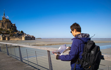  Asian man traveler holding and looking the  map on  street at Mont-Saint-Michel, Normandy,France