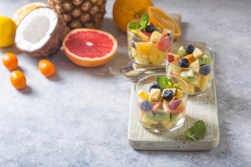 Fototapeta na wymiar Fruit salad in glasses, fresh summer foods , healthy organic orange kiwi blueberries pineapple coconut. top view