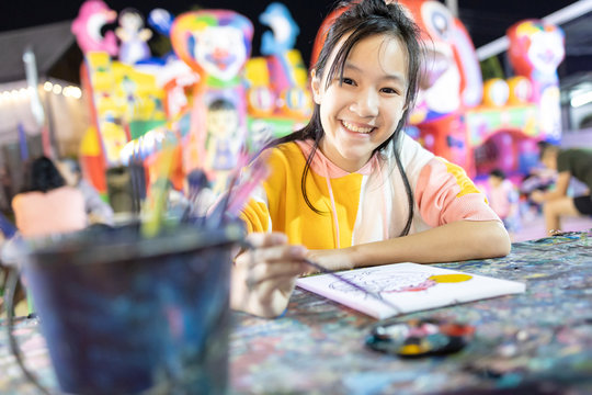 Happy asian child girl enjoy paint activities having fun,relax at night,smiling woman using watercolor with palette and paintbrush to painting,study, learn the art,concept development,hobby,activity