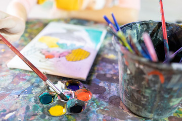 Closeup,hand of child girl with artistic tools on table,drawing and palette,paintbrush to painting...