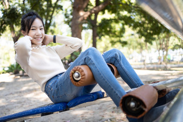 Beautiful asian child girl practicing fitness,doing sit up exercise for health and strength while visiting a city park,happy smiling female teenage doing abdominal sit ups in outdoor gym,health care