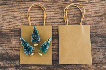 shopping bag with miniature Christmas trees around it, concept of festive season gifts