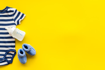 Baby background - blue color. Clothes and accessories for newborn boy on yellow table top-down frame copy space