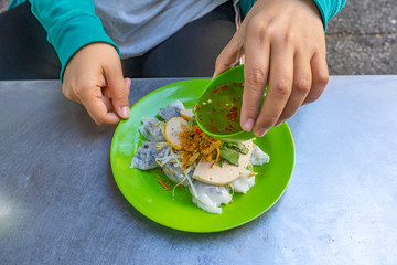 Woman eating Vietnamese food- Banh Cuon with chili fish sauce