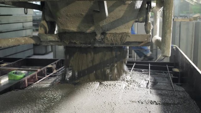 A large radio-controlled machine fills the concrete in form. Workers in the workshop of the House-building plant. Industrial interior. Concrete plant.