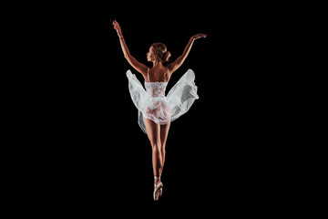 ballerina dancing in studio on a black background. dancer in motion with his back. isolated. young...