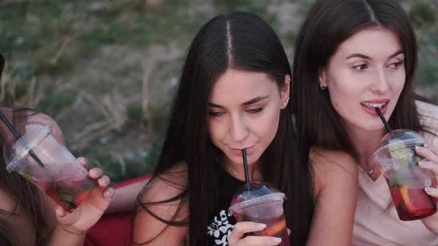 European girls are drinking cocktails and smiling. The young ladies are having fun together one summer sunset.