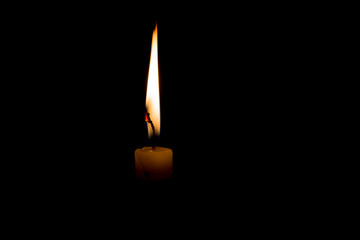 One light candle burning brightly in the black background