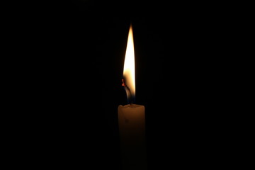 One light candle burning brightly in the black background