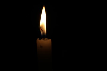 One light candle burning brightly in the black background