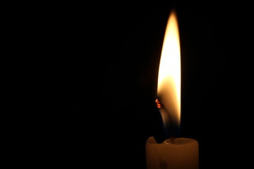 One light candle burning brightly in the black background
