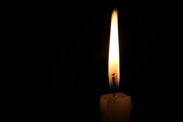 One light candle burning brightly in the black background