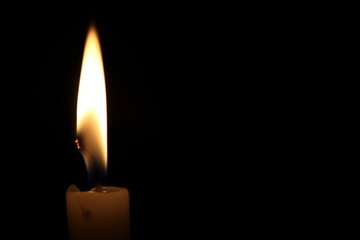 One light candle burning brightly in the black background