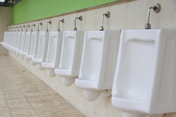 line of white porcelain urinals in public toilets