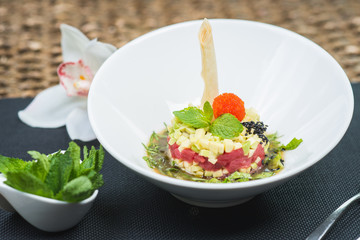 Classic traditional tartar salad laid in a round shape, stylish serving in an oriental style table in a restaurant.