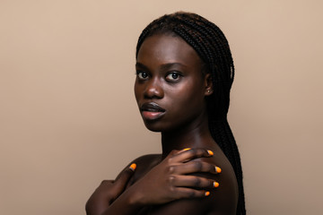 Young african girl with perfect skin on beige background.