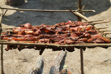 pieces of pork grilled on a simple wooden grill