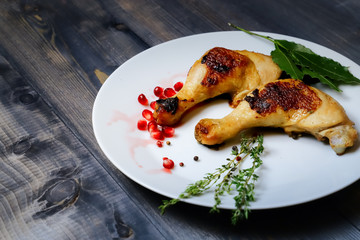On a white dish on a dark wooden tabletop are two fried chicken