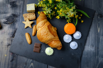 In the center of composition French croissant On graphite colors of flat stone meringue tiles there...