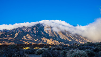 Spain, Tenerife, Volcanic mountain teide with blue sky and covered by fog clouds on sunny day in winter in caldera, a magical nature landscape