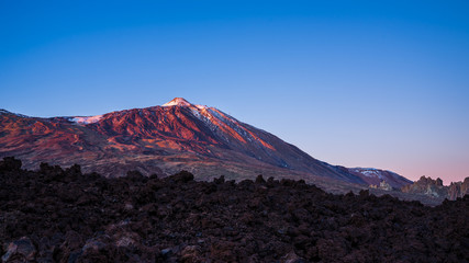 Spain, Tenerife, Volcano mount teide peak in magical red alpenglow sunset light behind endless lava...