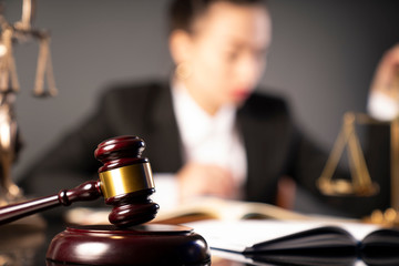 Young lawyer during work in chamber. Gavel, scale and Themis statue on the table.