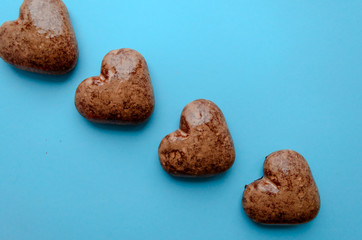Valentine's flat lay with love chocolate gingerbread heart on colorful blue background, greeting card copy space top view. The celebration of Valentine's Day.