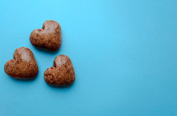Valentine's flat lay with love chocolate gingerbread heart on colorful blue background, greeting card copy space top view. The celebration of Valentine's Day.